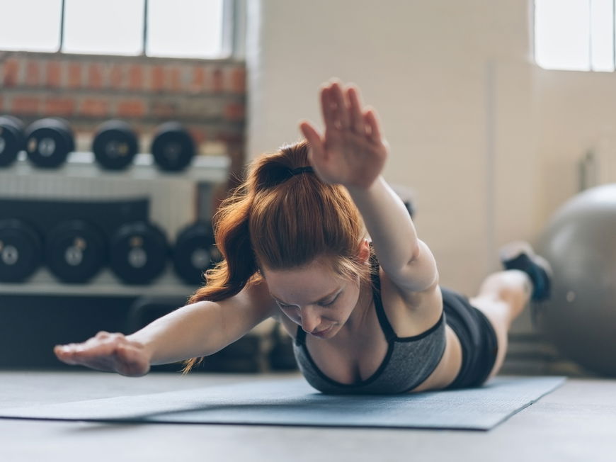 Frau macht Superman-Übung im Fitnessstudio