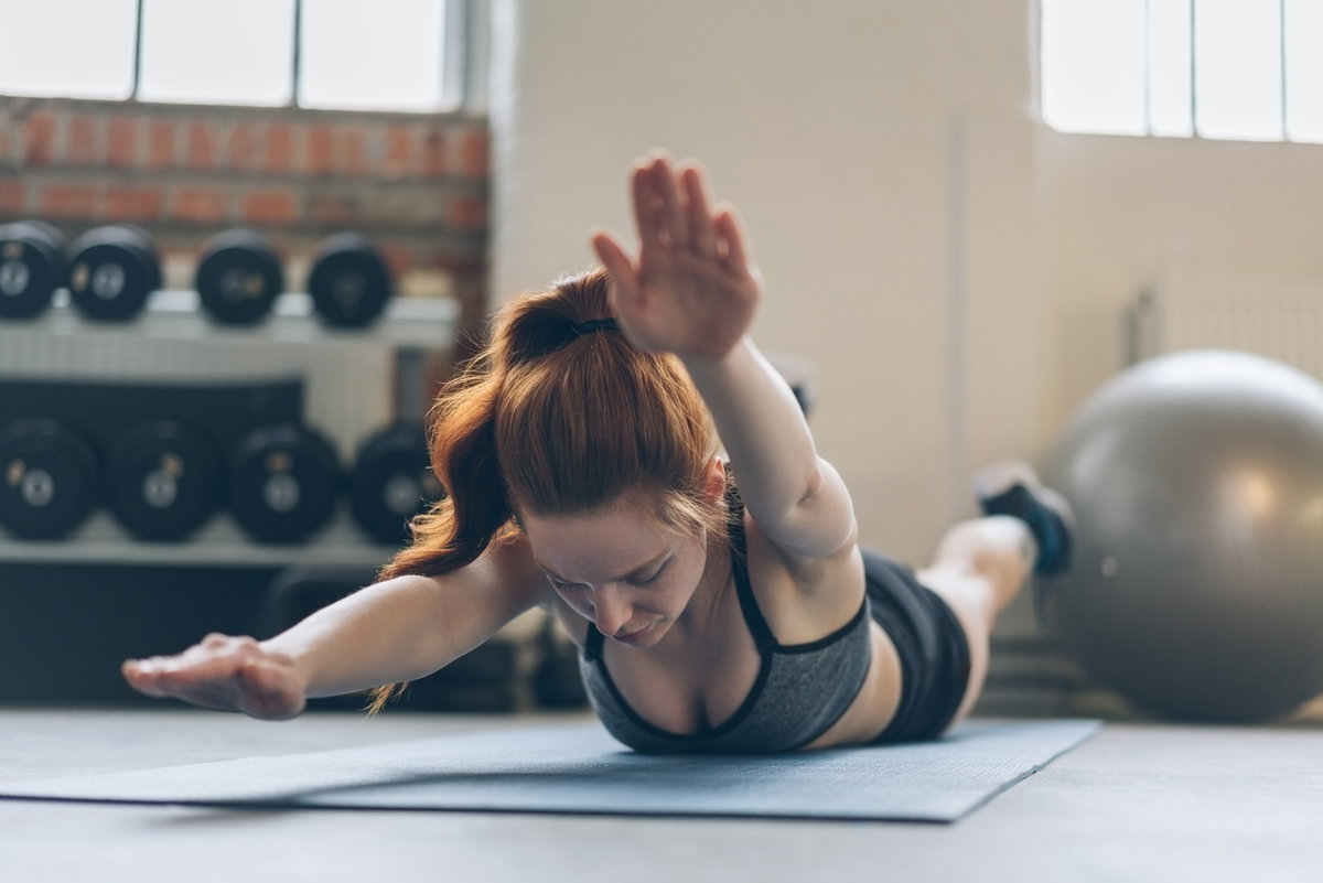 Frau macht Superman-Übung im Fitnessstudio