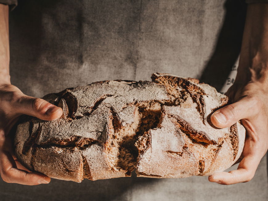 Mann bricht ein frischgebackenes Brot durch
