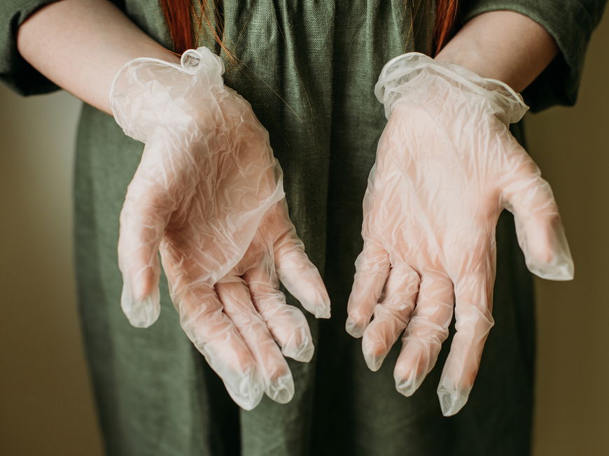 Ärztin hält in Latexhandschuhe verpackte Hände mit den Handflächen nach vorn in die Kamera