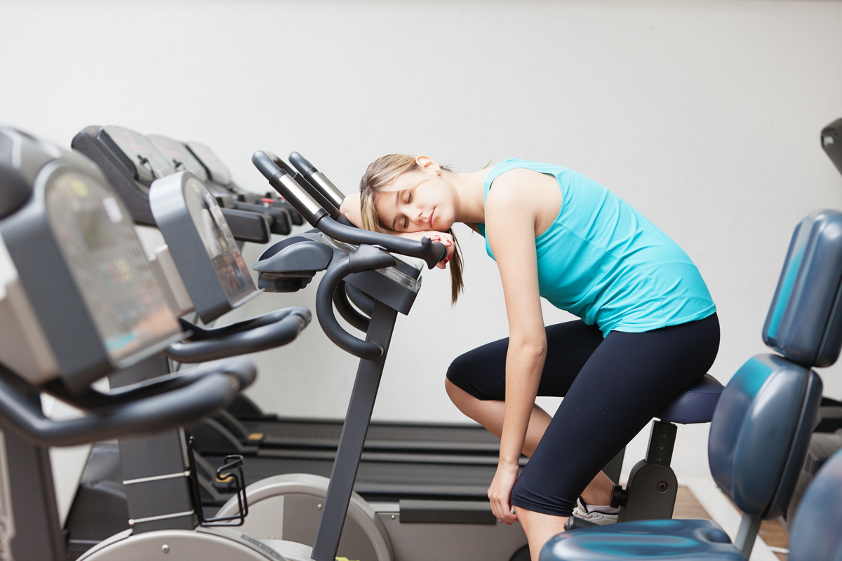 Frau sitzt müde auf einem Hometrainer