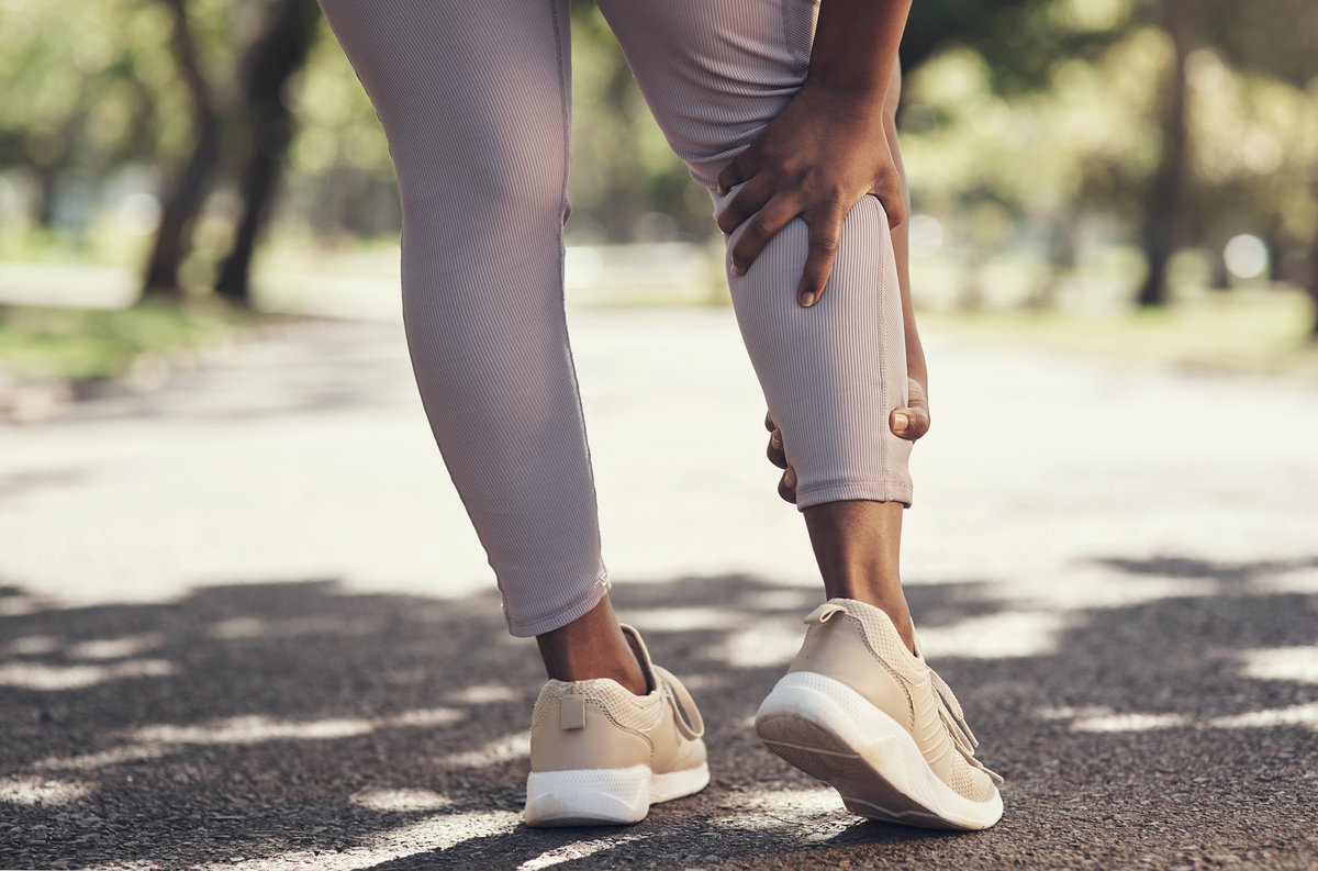 Eine Joggerin hält sich die schmerzende Wade