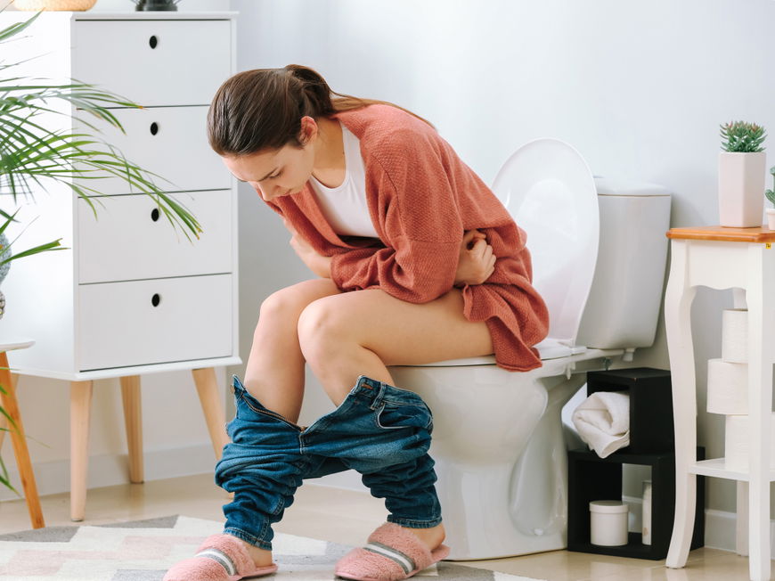 Frau sitzt auf Toilette