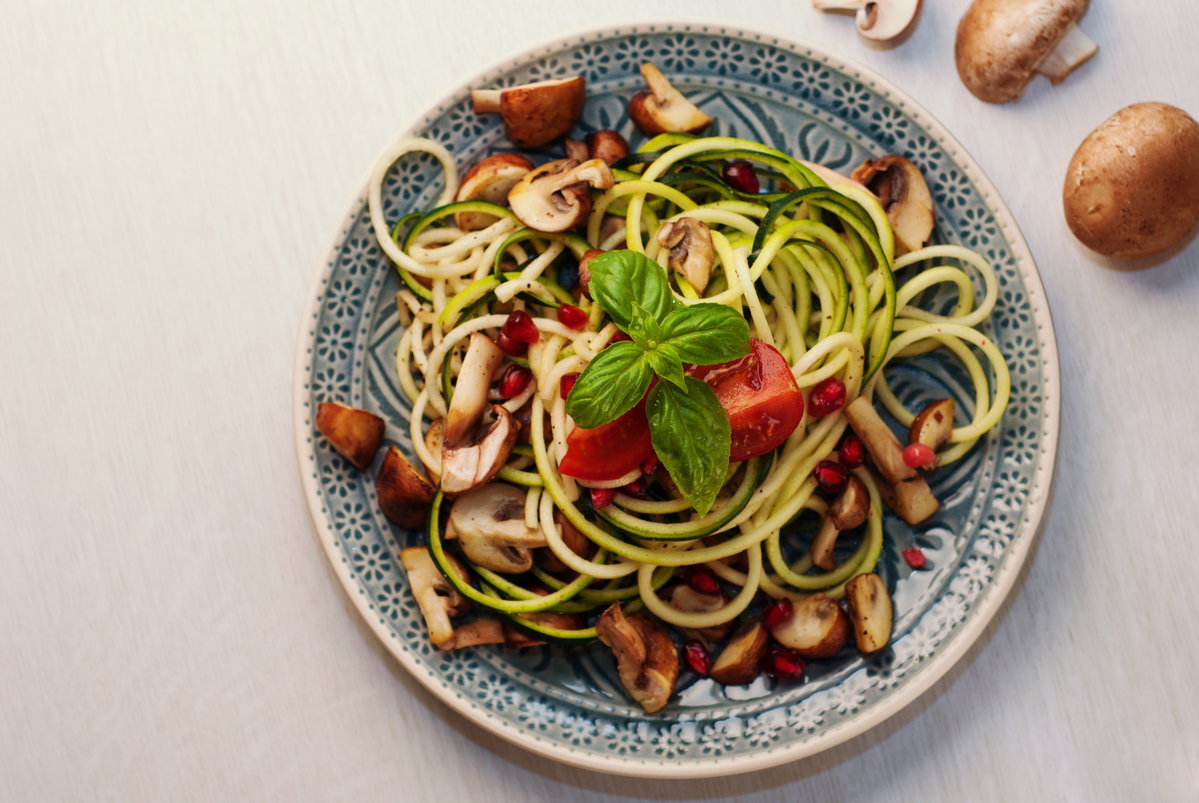 Rohe Zucchini in einem Salat mit Pilzen und Tomaten