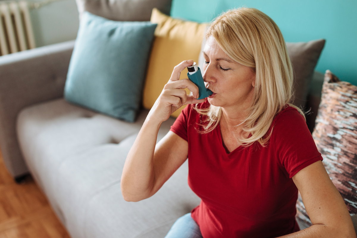 Frau hat allergisches Asthma und nutzt einen Inhalator.