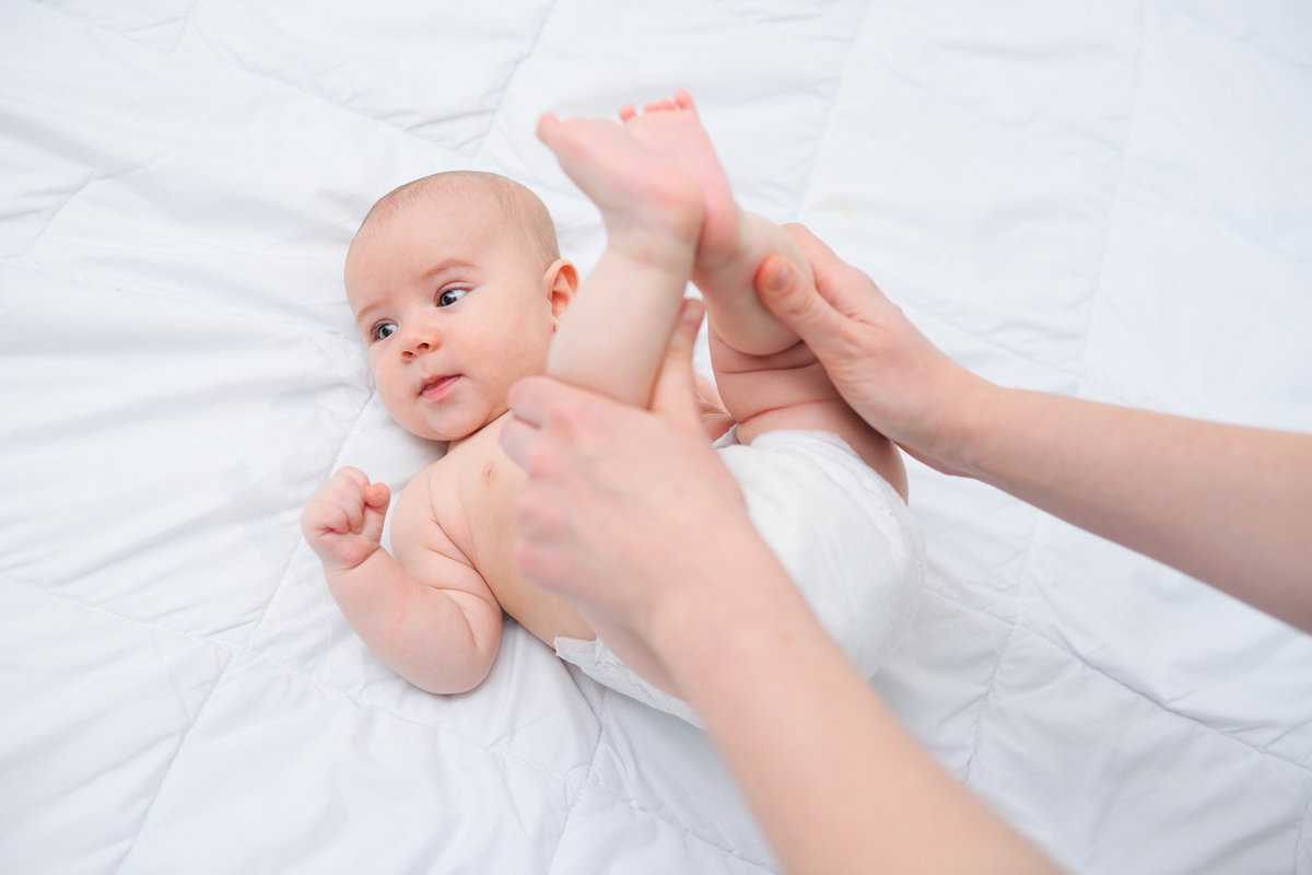 Ein Baby hat Bauchschmerzen und wird massiert.
