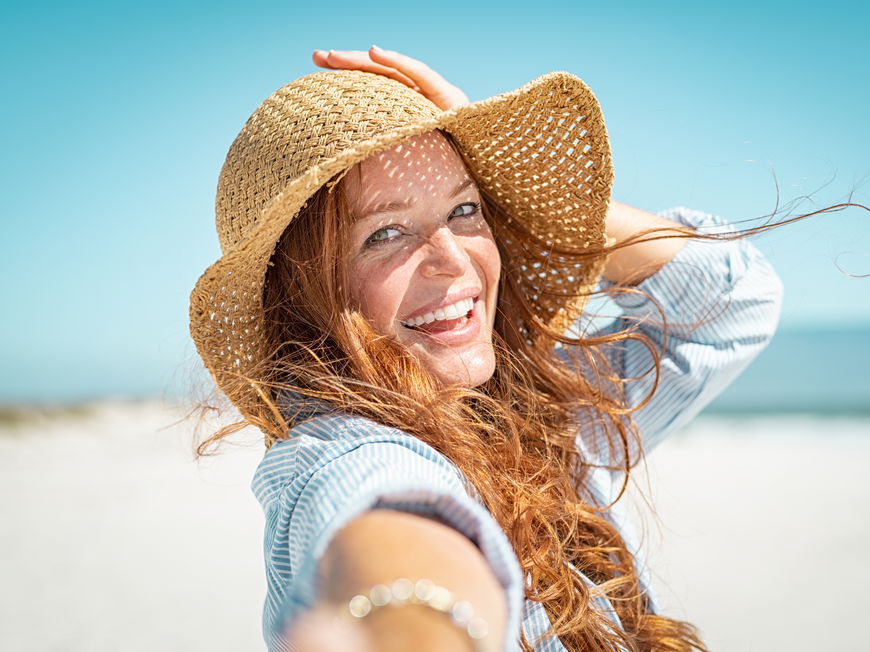 Frau mit Sonnenhut am Strand