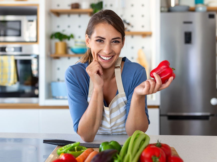 Frau in der Küche hält Paprika in den Händen