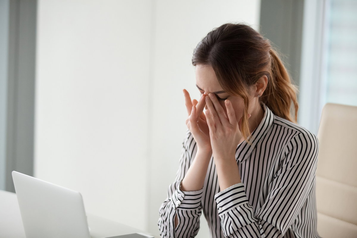 Frau vor Laptop reibt sich trockene Augen