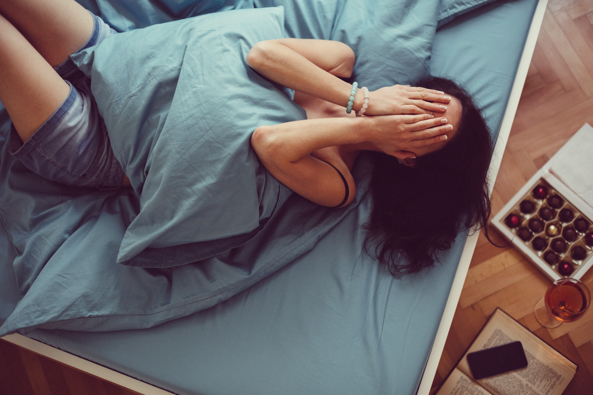 Frau liegt im Bett und weint
