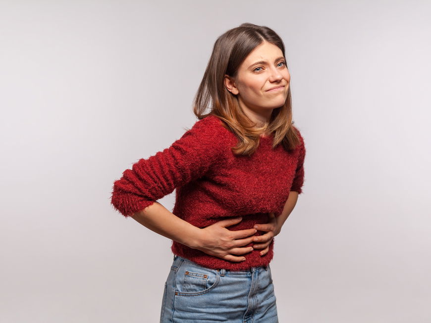 Frau hält sich den Bauch, weil sie Hunger hat