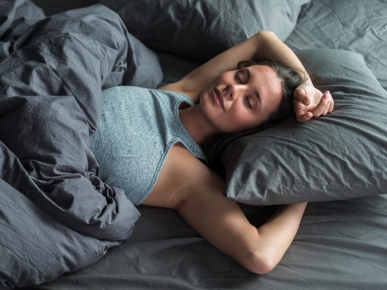 Junge Frau liegt im Bett und schläft.