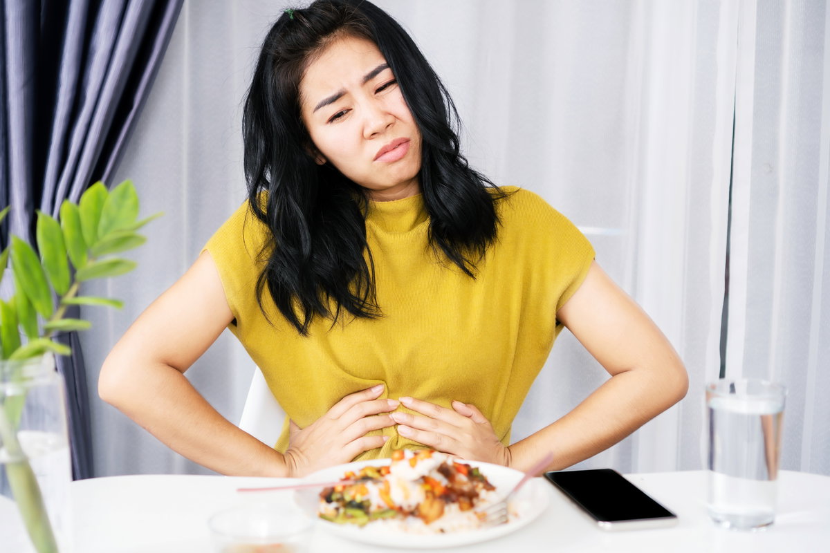 Frau hält sich den Bauch beim Essen
