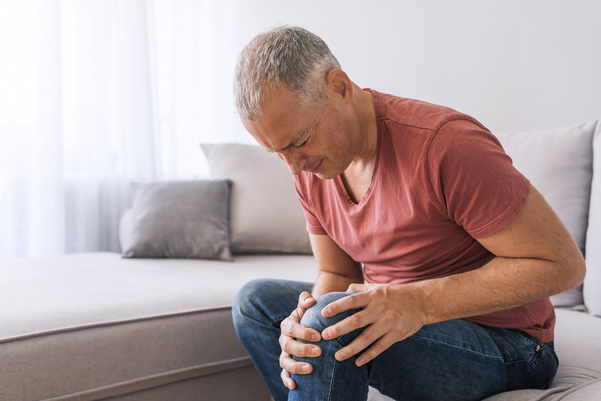 Ein Mann hält sich vor Schmerzen wegen einer Gelenkerkrankung das Knie.