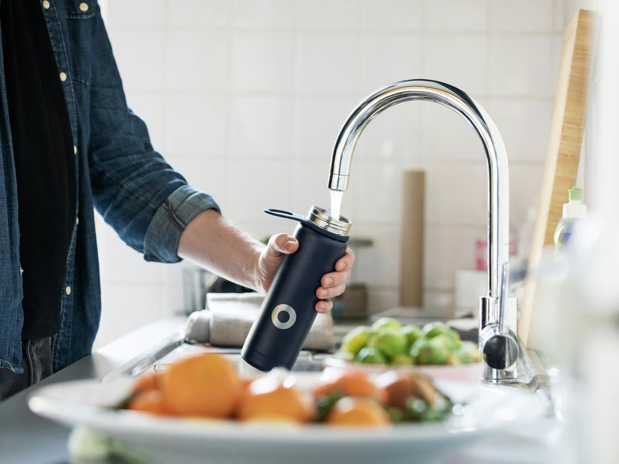Mann füllt Flasche am Wasserhahn auf