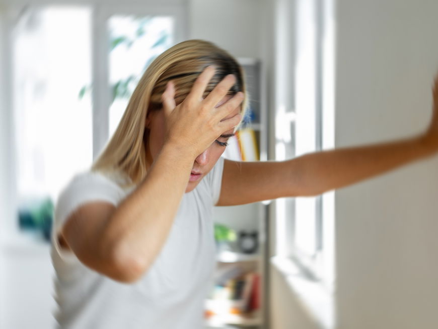 Frau fühlt sich unwohl und stützt sich an der Wand ab