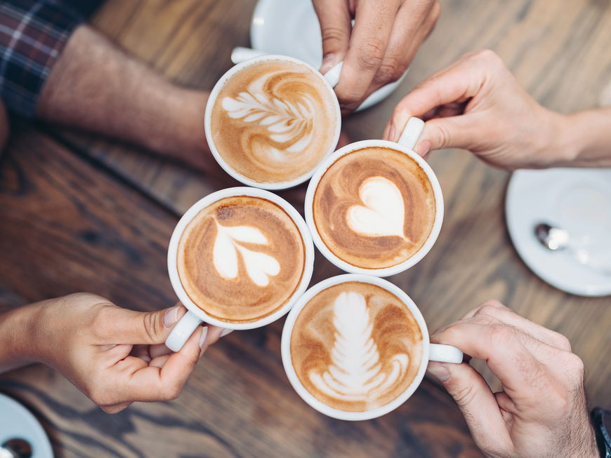 Hände, die mit Kaffee anstoßen