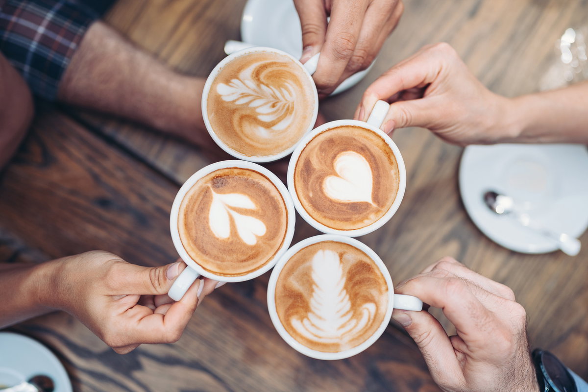 Hände, die mit Kaffee anstoßen