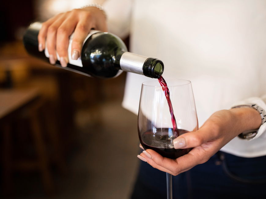 Frau schenkt sich ein Glas Wein ein