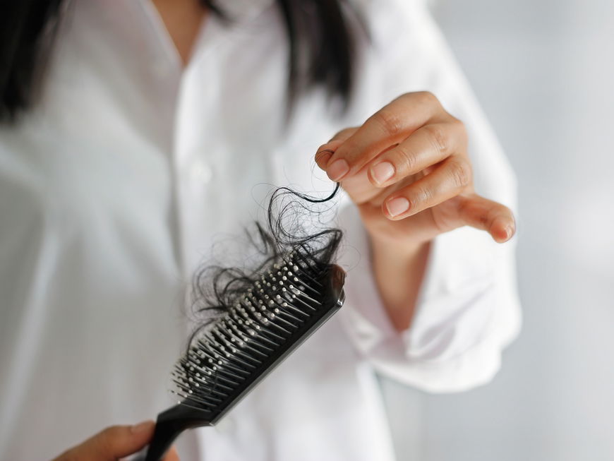 Frau mit Bürste, in der ein Haarbüschel steckt