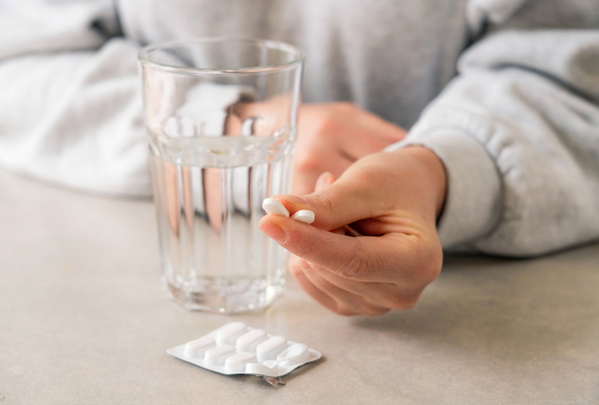 Hand mit zwei Ibuprofen darin