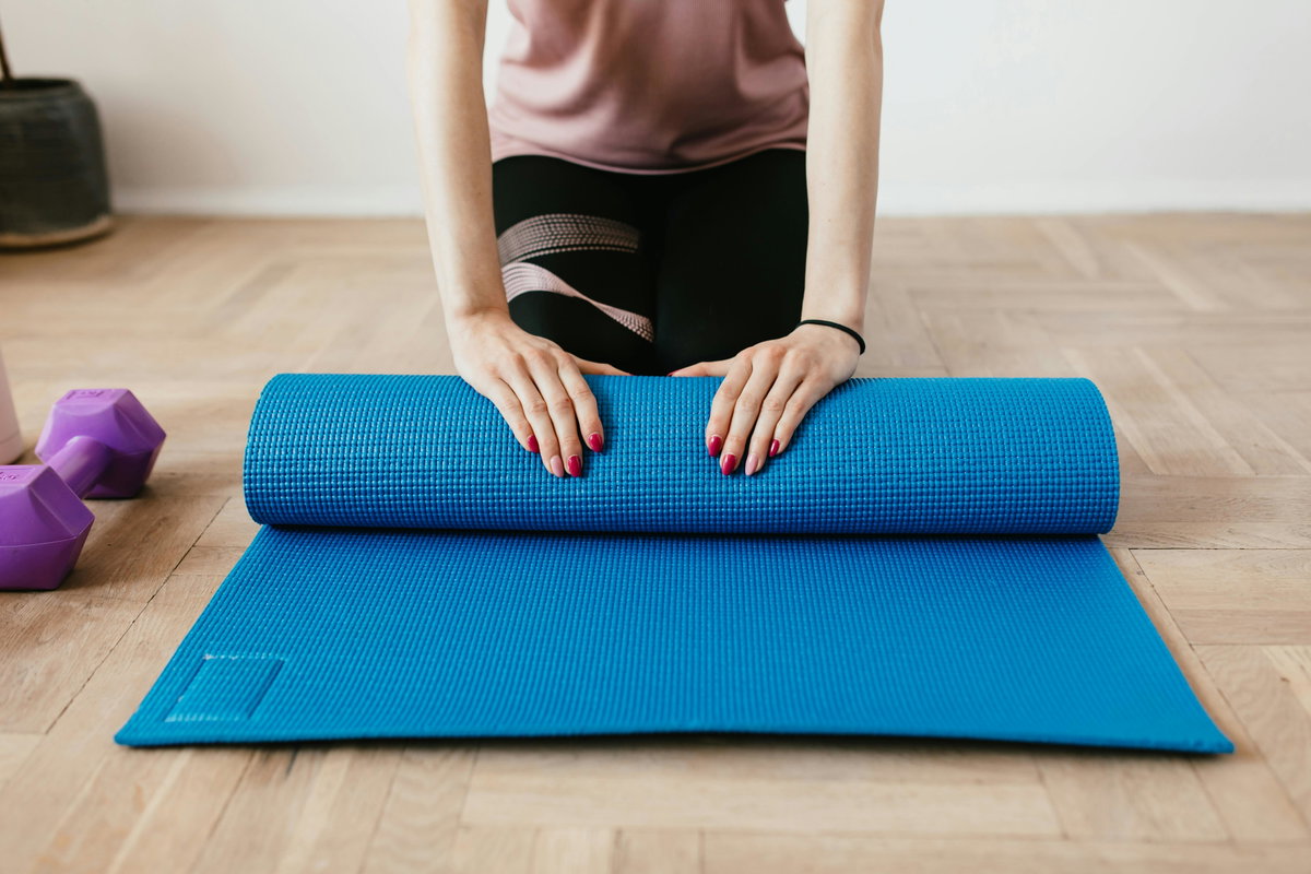 Frau rollt Sportmatte zusammen