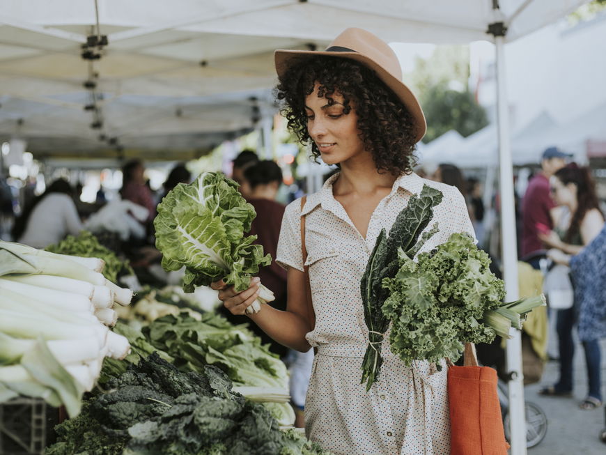 Frau kauft Kohlgemüse auf dem Wochenmarkt