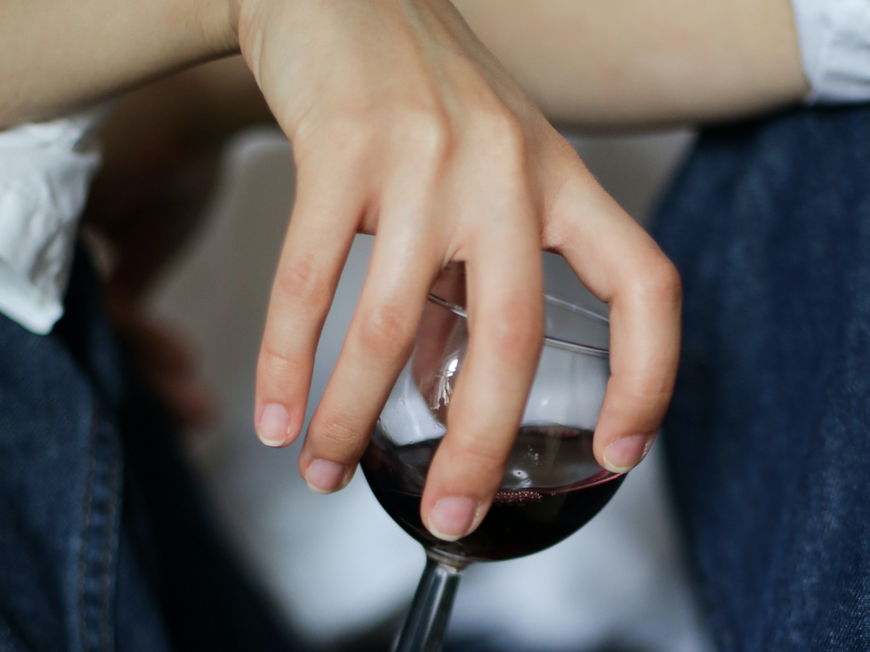 Eine Frau hält lässig ein Glas Wein in der Hand