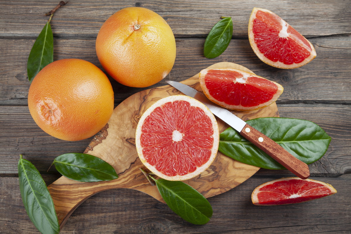 Grapefruit im Ganzen und aufgeschnitten mit einem Messer