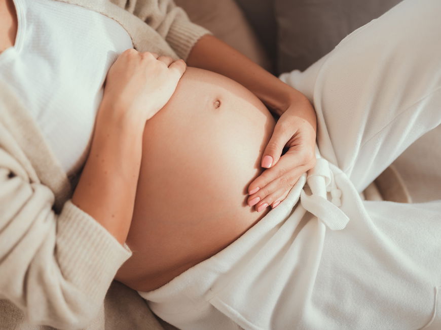 Eine schwangere Frau hält ihre Hände auf ihrem Bauch