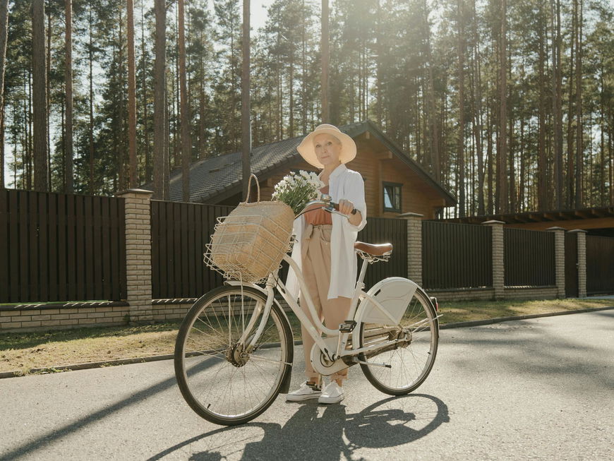 Frau ab 50 steht neben ihrem Fahrrad