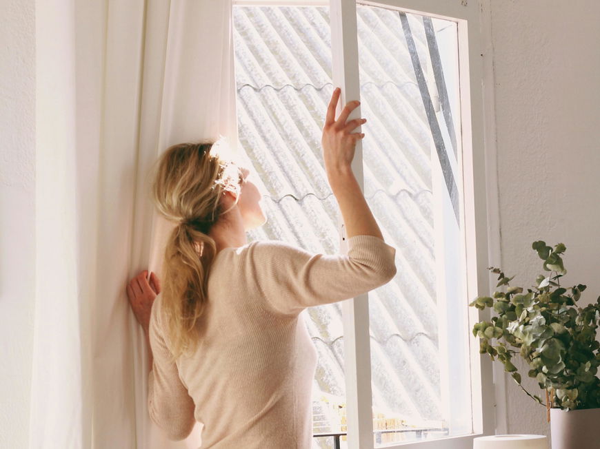 Frau öffnet Fenster. Sicherheit vor Einbruch