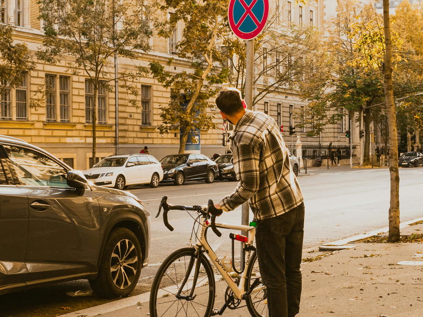 Mann mit Fahrrad steht in der Stadt und schaut sich ein Verkehrsschild an