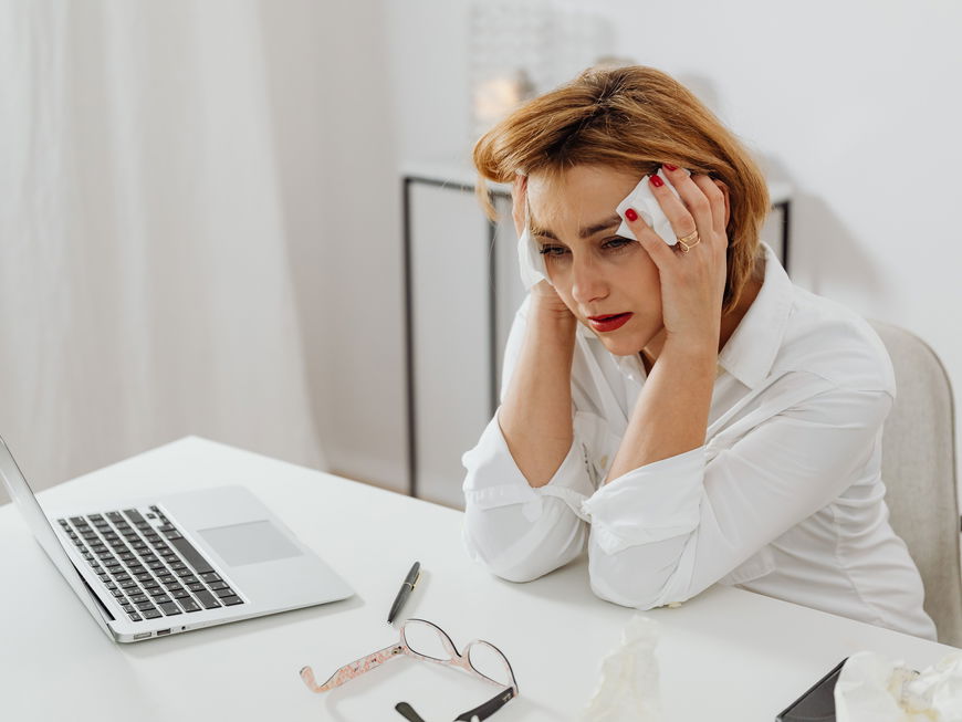 Frau in der Menopause schwitzt im Büro