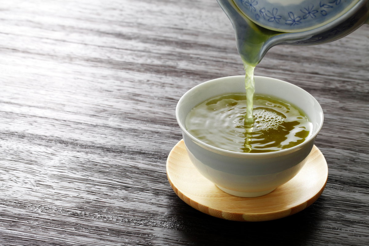 Grüner Tee wird in eine Tasse gegossen
