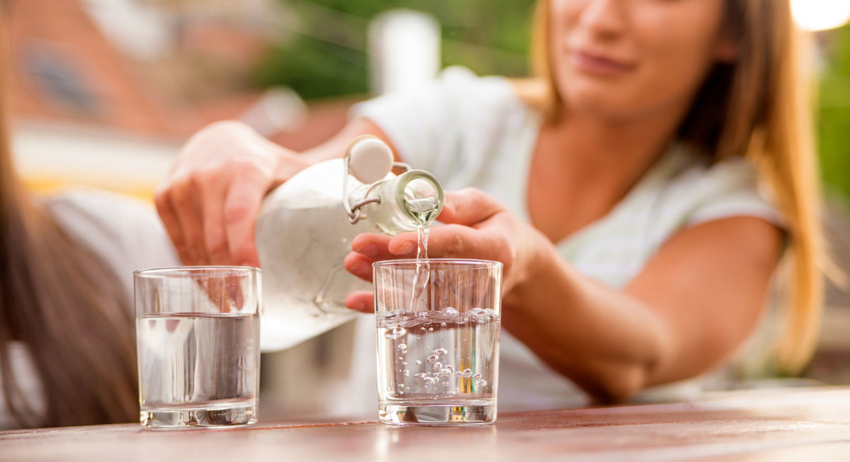 Frau gießt Wasser in Glas ein