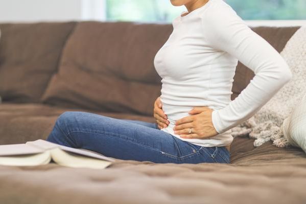 Frau hält sich die Hände vor dem Bauch.
