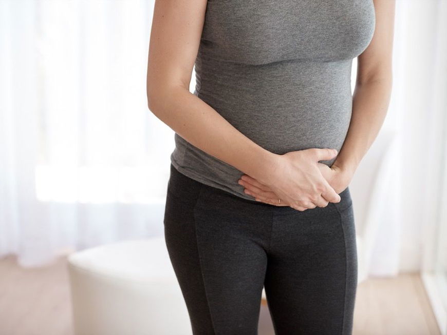 Schwangere Frau hält sich die Hände vor dem Bauch.