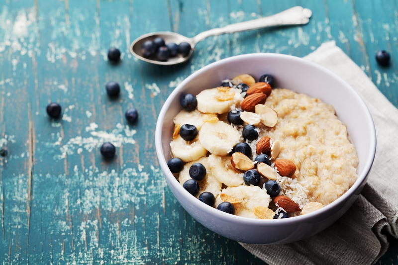 Overnight-Oats ist einer Schüssel mit Blaubeeren, Banane und Mandeln.