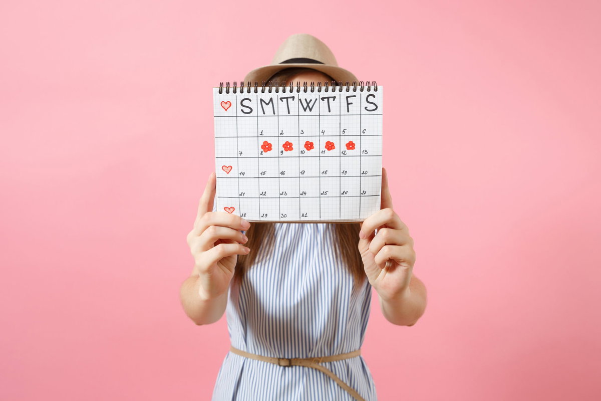 Frau mit Menstruationskalender in der Hand
