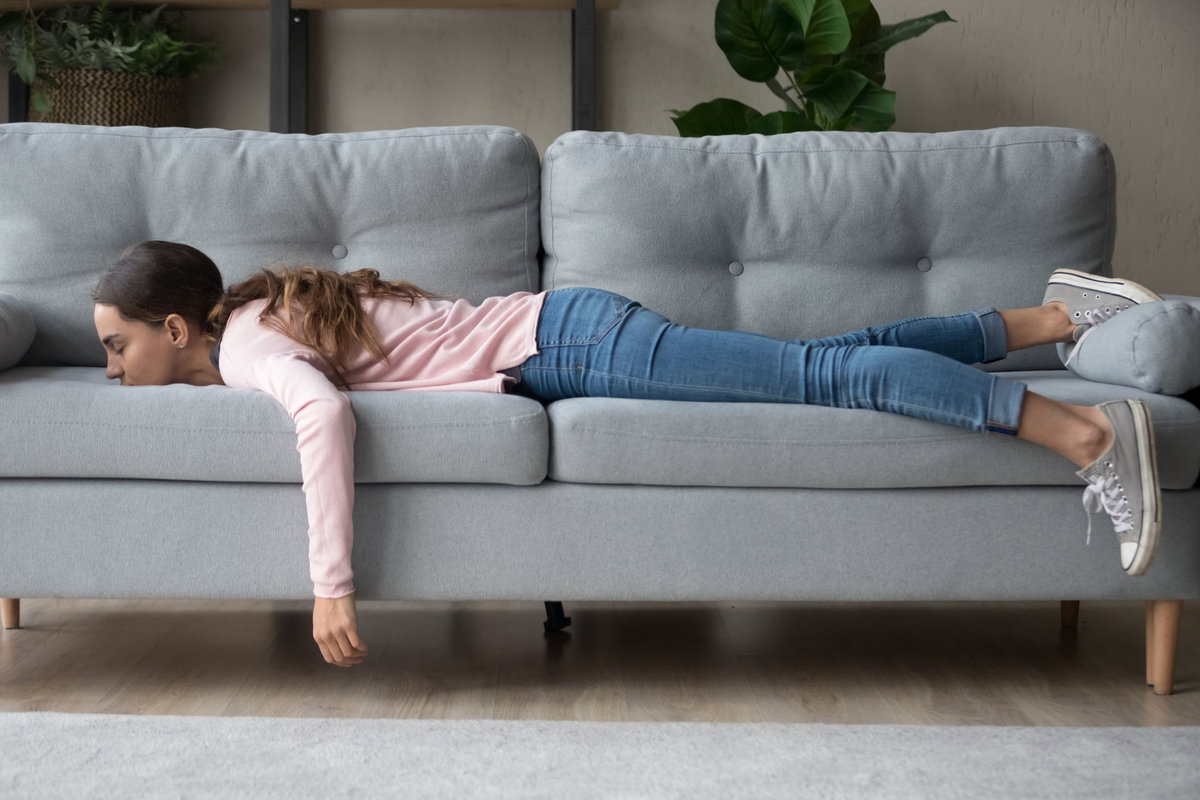 Boreout Symptom: Frau liegt bäuchlings auf dem Sofa
