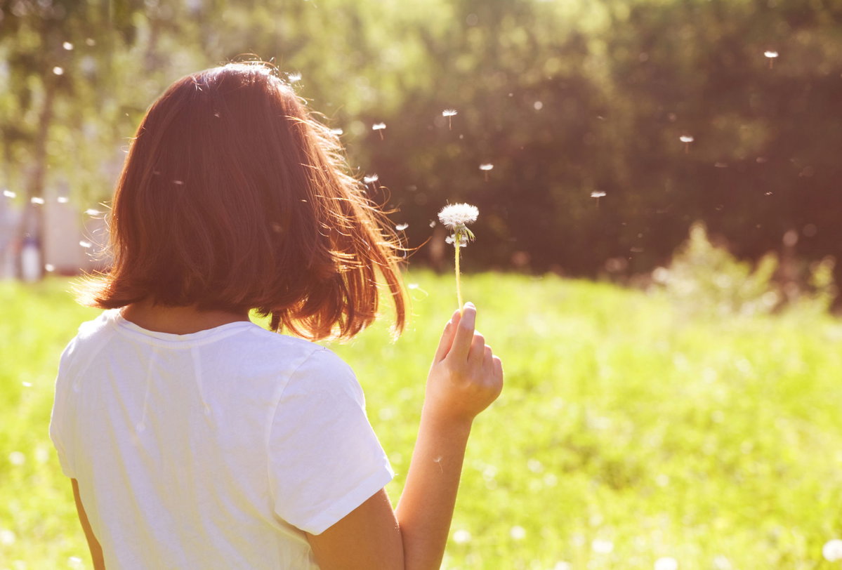 Frau auf Wiese mit Pusteblume