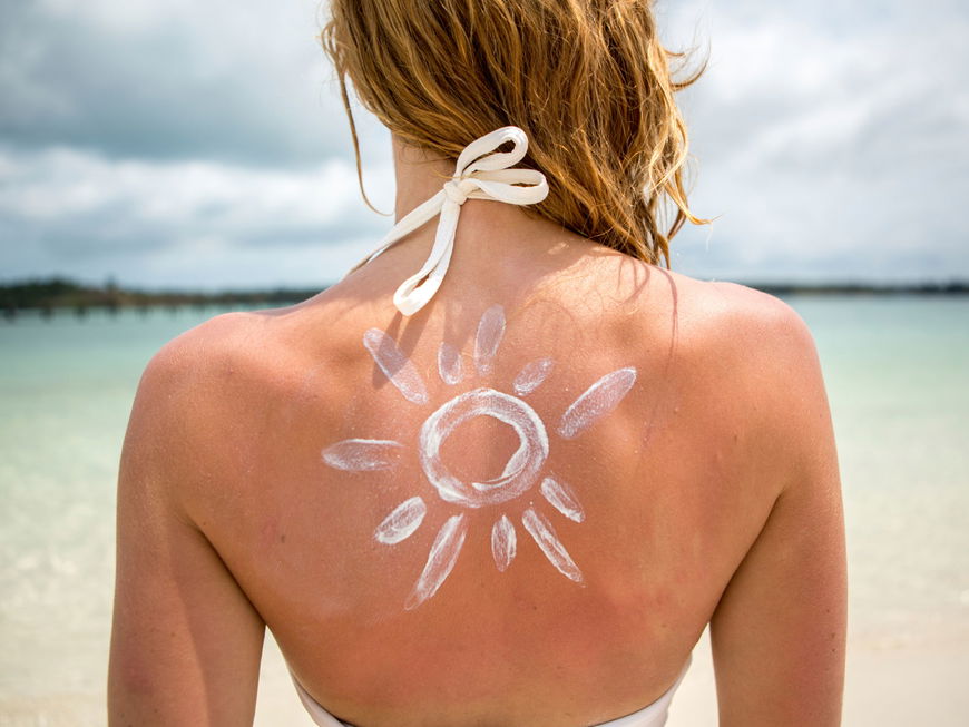Frau mit Sonnencreme auf dem Rücken