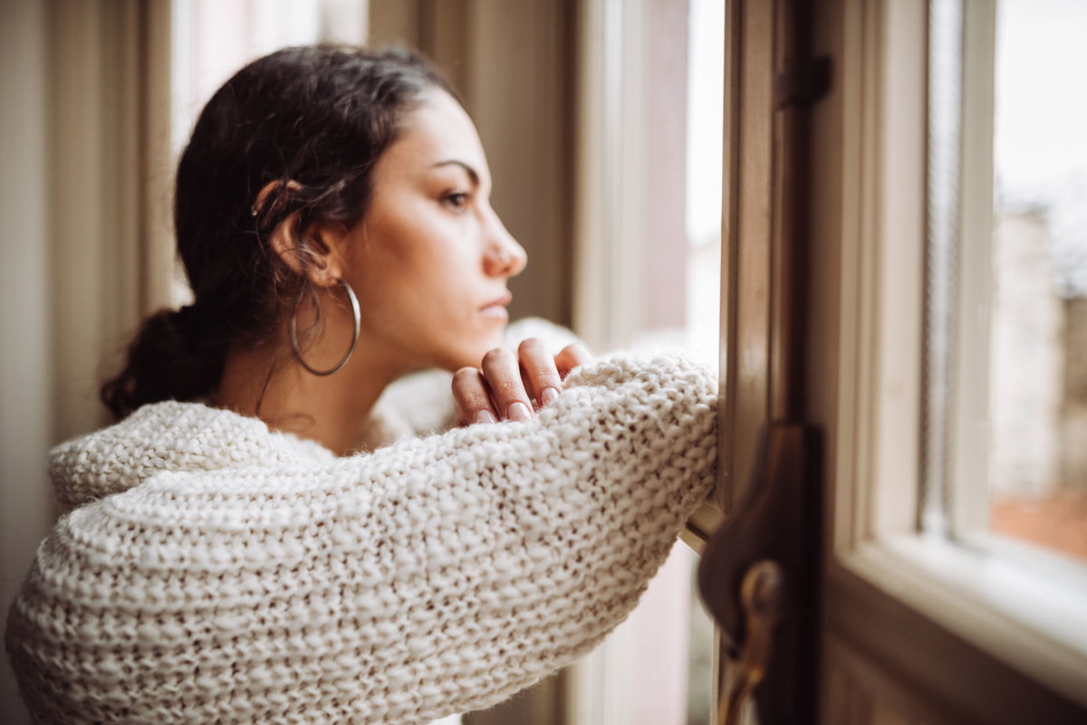 Frau steht am Fenster