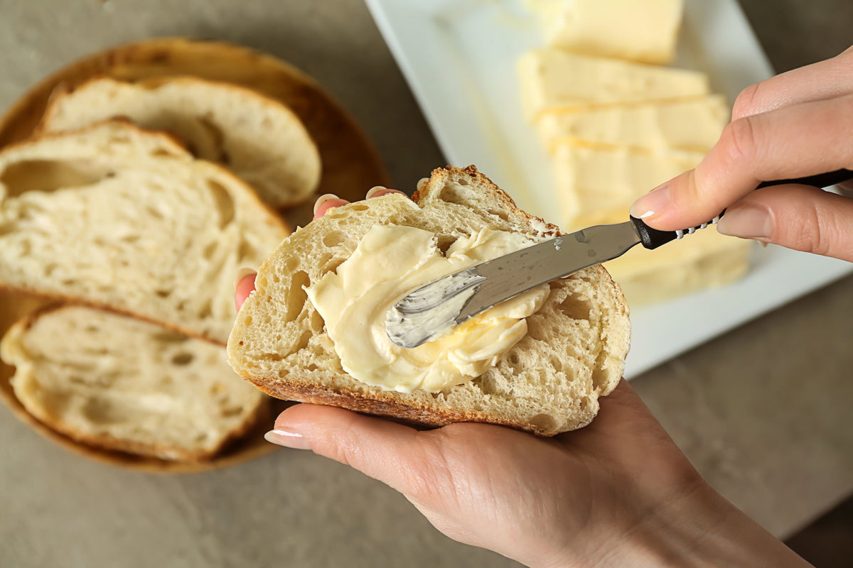 Frau schmiert Butter auf eine Scheibe Brot