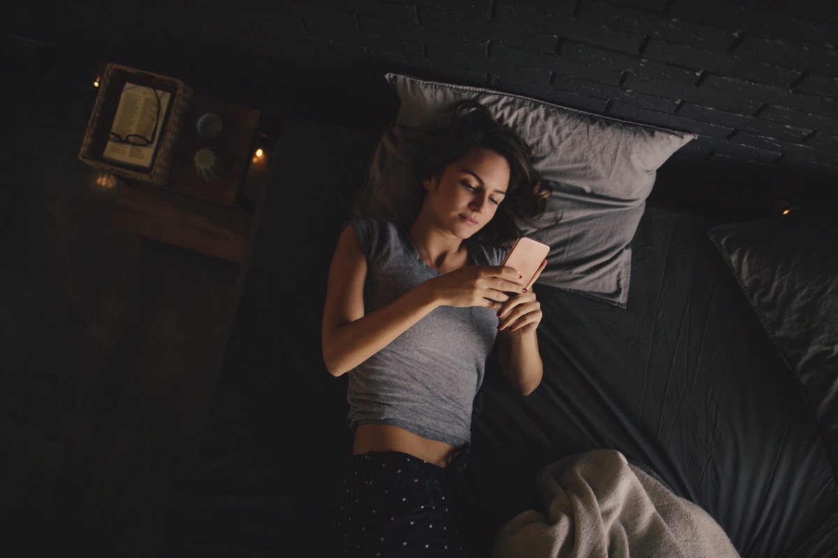 Frau mit Smartphone im Bett