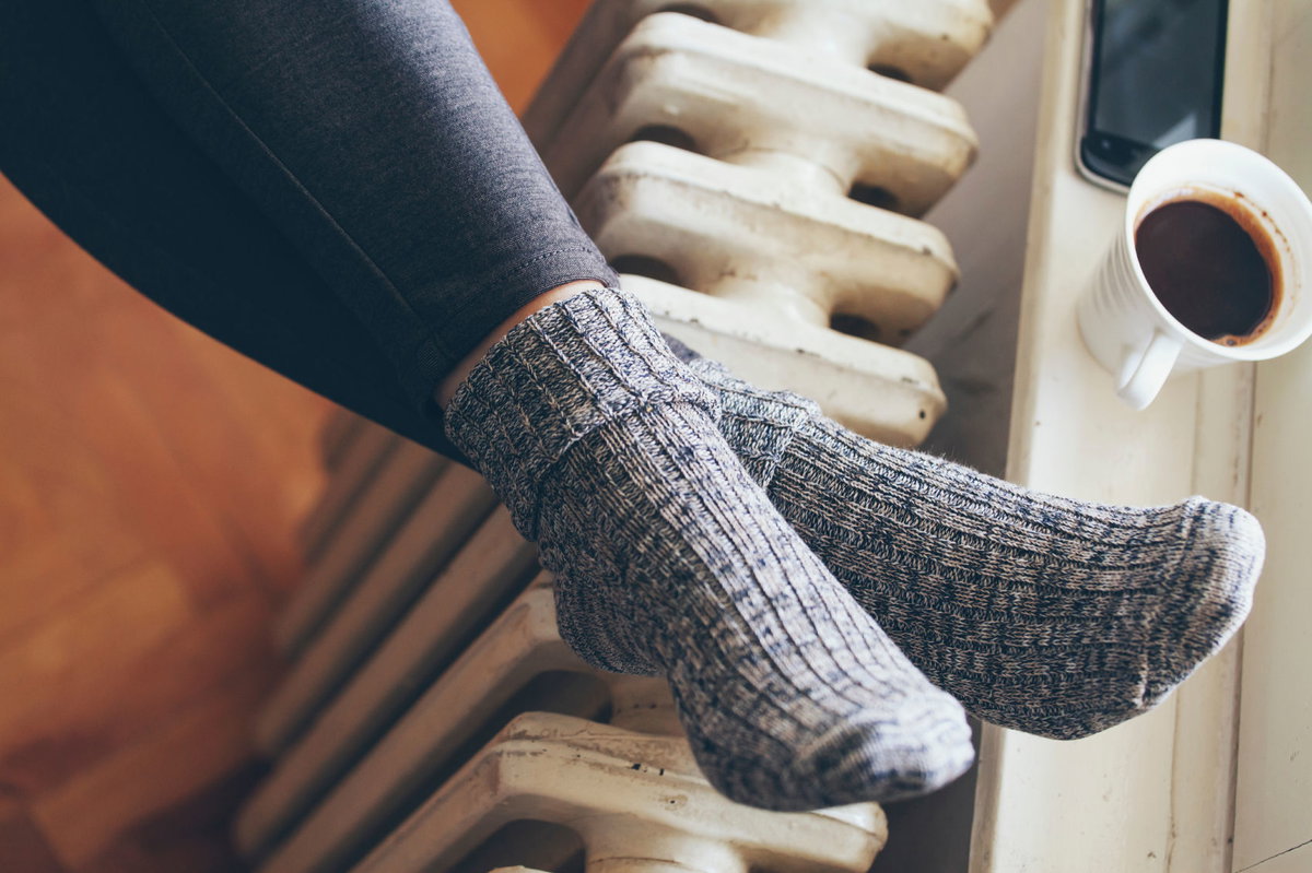Frau mit Wollsocken Füße auf Heizung