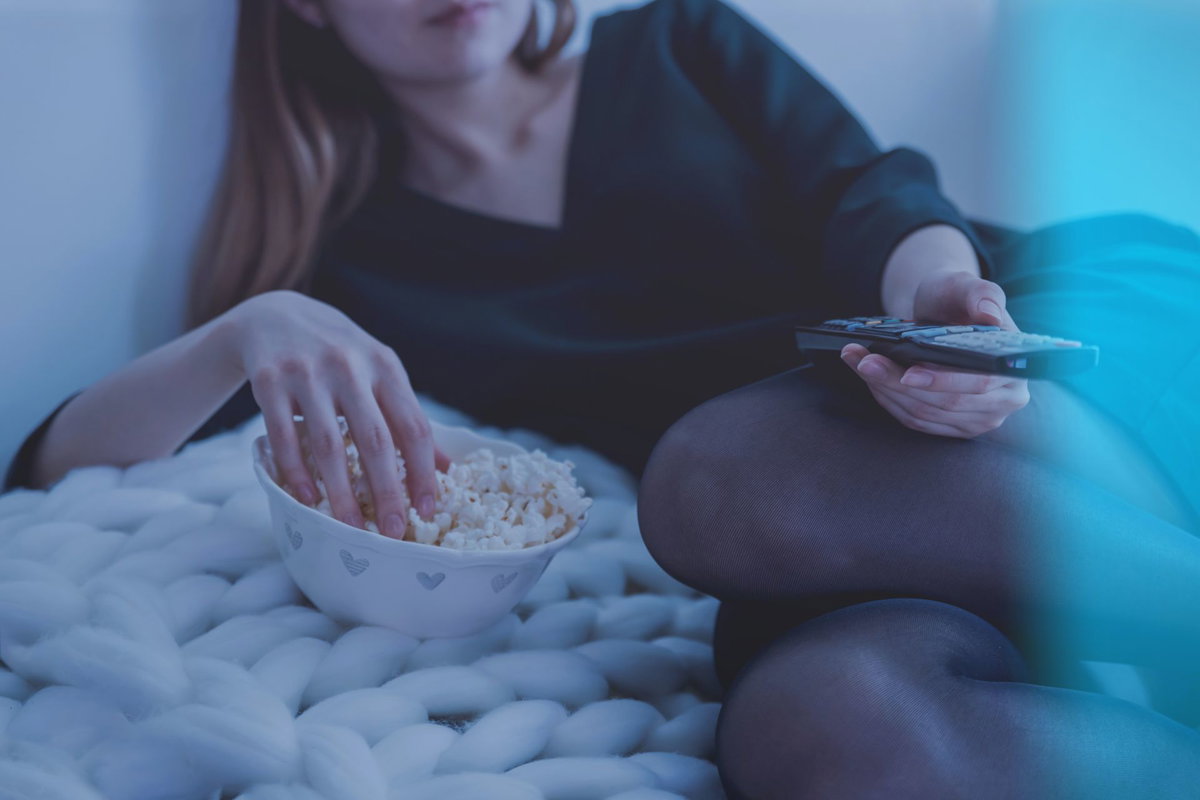Frau guckt TV mit Popcorn
