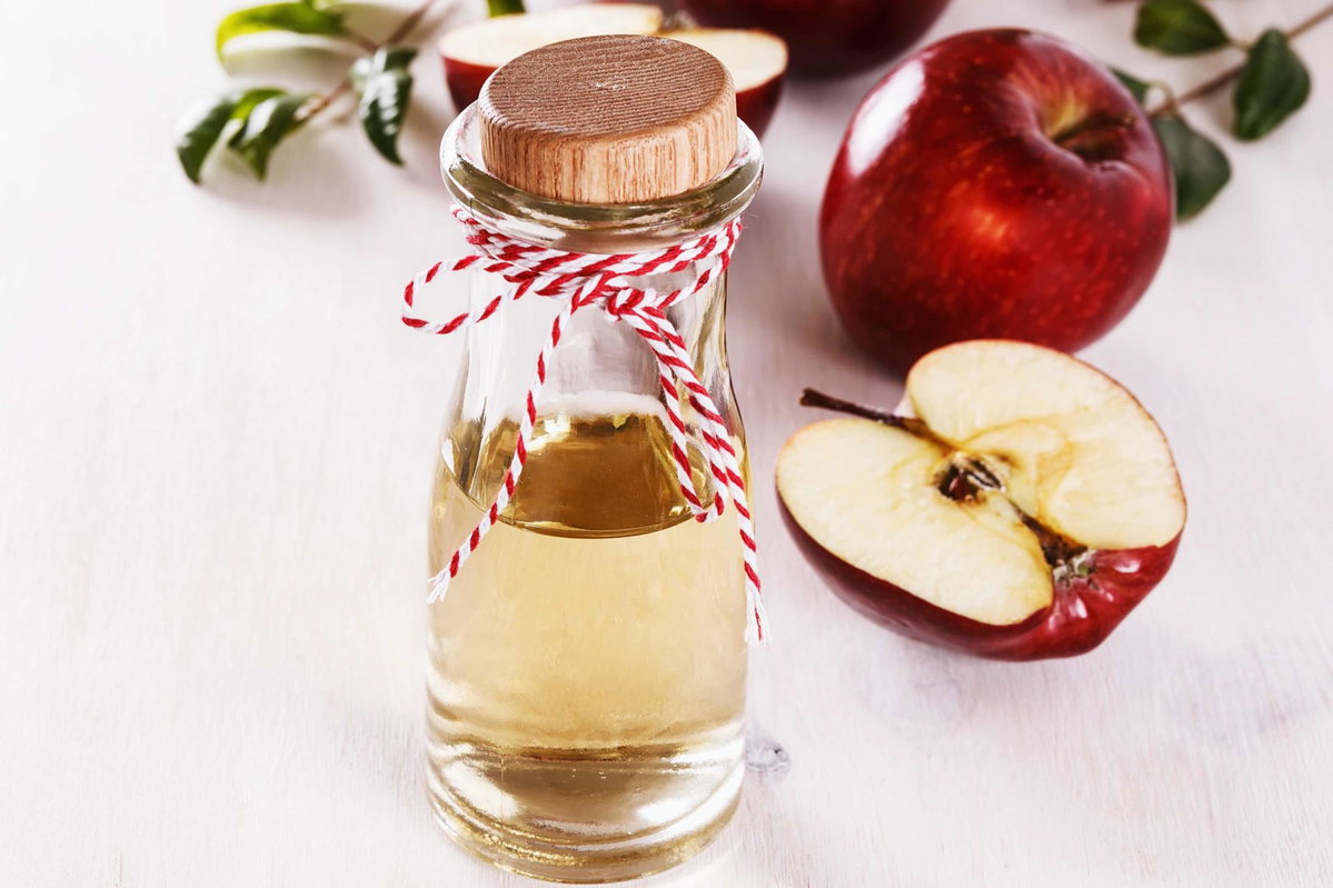 Flasche mit Apfelessig und Äpfel